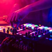 Close up of DJ hands on dj console mixer during concert in the night club